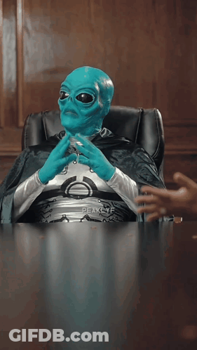 A Blue Alien Is Sitting At A Table With The Word But Visible GIF