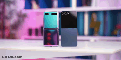 A Blue And A Black Flip Phone Are Sitting On A Table GIF