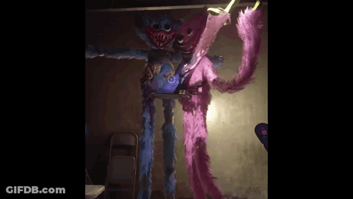 A Blue And Pink Stuffed Animal Are Standing Next To Each Other In A Room . GIF