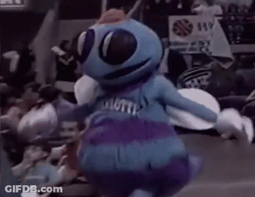 A Blue And Purple Mascot Is Dancing In Front Of A Crowd . GIF
