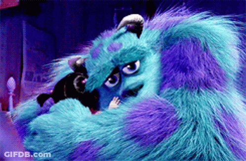 A Blue And Purple Monster From Monsters Inc Is Laying On A Bed GIF