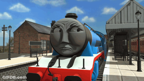 A Blue And Red Train With An Angry Face Is On The Tracks GIF