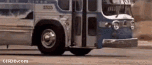 A Blue And White Bus Is Driving Down A Street . GIF
