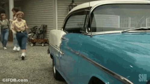 A Blue And White Car Is Parked In A Driveway Next To A Group Of People . GIF