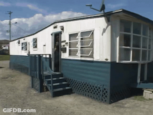 A Blue And White Mobile Home With Stairs Leading Up To The Door GIF
