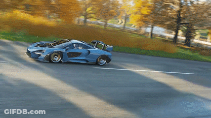 A Blue And White Sports Car Is Driving Down A Road GIF