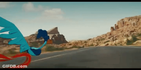 A Blue Bird Is Flying Over A Road In The Desert . GIF