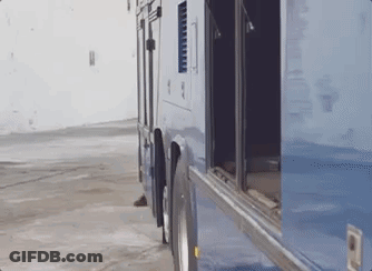 A Blue Bus With The Doors Open Is Parked In A Parking Lot . GIF