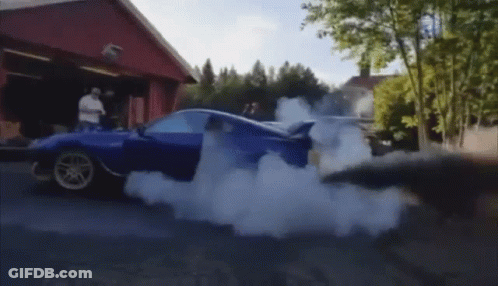A Blue Car Is Doing A Burnout On A Street GIF