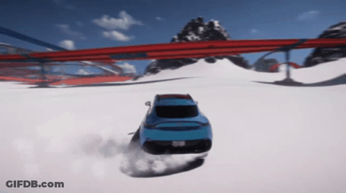 A Blue Car Is Driving Down A Snowy Road With Mountains In The Background GIF