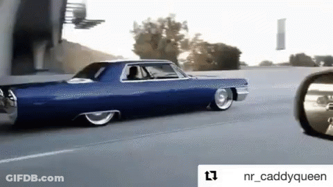 A Blue Car Is Driving Down The Road Next To A Rear View Mirror GIF