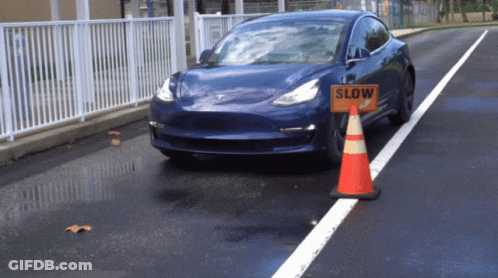 A Blue Car Is Driving Past A Slow Sign GIF