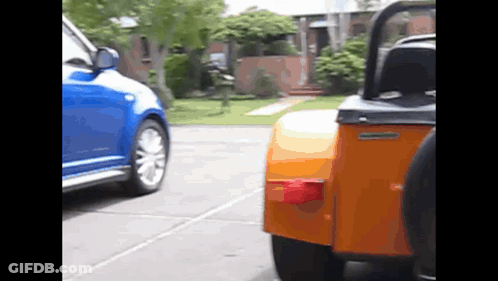 A Blue Car Is Parked Next To An Orange Vehicle GIF