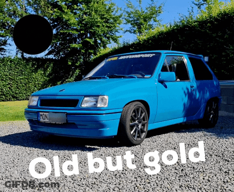 A Blue Car Is Parked On Gravel Next To A Sign That Says Old But Gold GIF