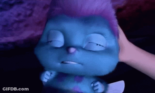 A Blue Cartoon Character With Purple Hair Is Being Held By A Person GIF