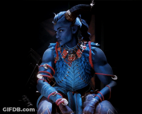 A Blue Demon With Horns And A Necklace Is Sitting In The Dark GIF