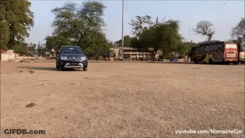 A Blue Jeep Is Driving Down A Dirt Road In Front Of A Bus GIF