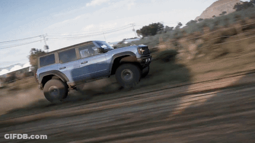 A Blue Jeep Is Driving Through A Dirt Field GIF