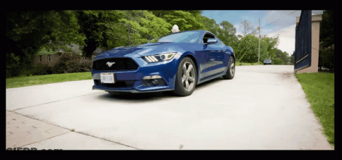 A Blue Mustang Is Driving Down A Road With A License Plate That Says ' Tcj ' On It GIF