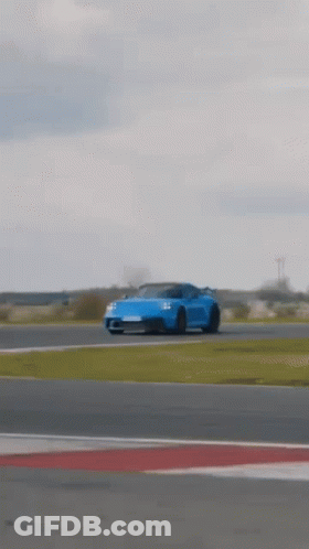 A Blue Porsche 911 Gt3 Is Driving On A Race Track . GIF
