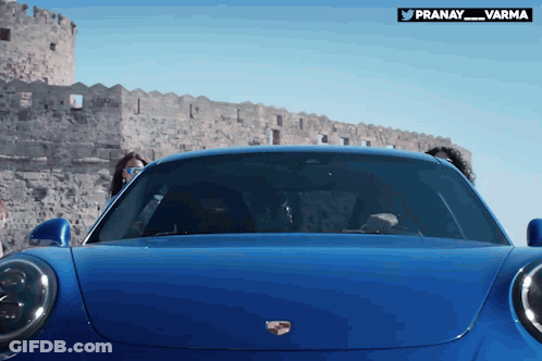 A Blue Porsche Car Is Parked In Front Of A Castle GIF