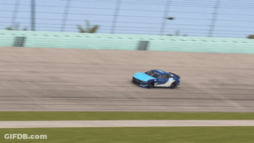 A Blue Race Car With The Word Ford On The Side Is Driving Down A Track GIF