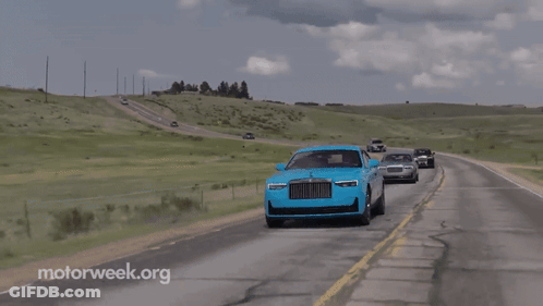 A Blue Rolls Royce Is Driving Down The Road With Other Cars GIF