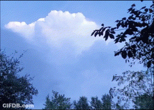 A Blue Sky With Trees In The Foreground And A Cloud In The Middle GIF