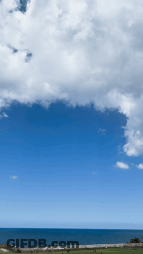 A Blue Sky With White Clouds Over The Ocean And A Golf Course In The Foreground GIF