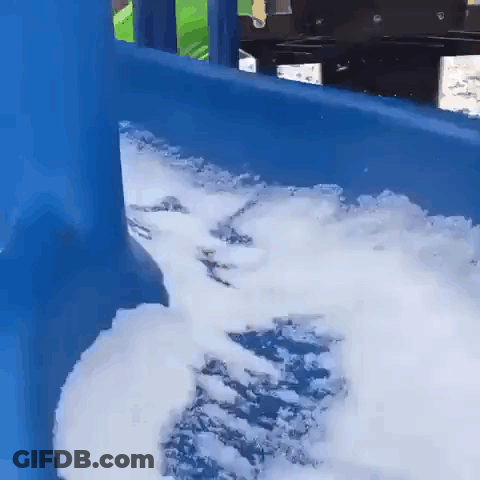 A Blue Slide With Foam Coming Out Of It Is Covered In Snow . GIF