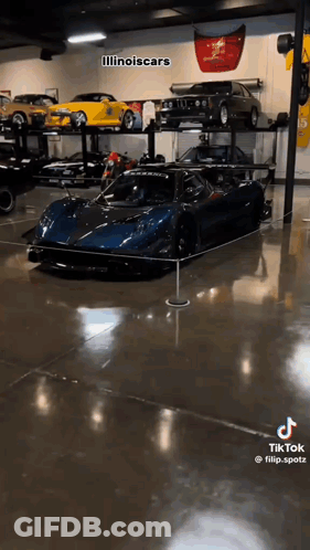 A Blue Sports Car Is Displayed In A Garage . GIF