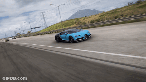 A Blue Sports Car Is Driving Down A Highway With A Mountain In The Background GIF