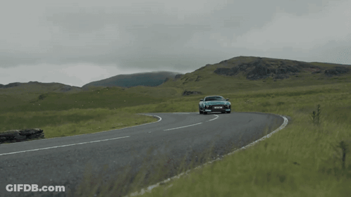 A Blue Sports Car Is Driving Down A Road With Mountains In The Background And A License Plate That Says Ycs Jml GIF