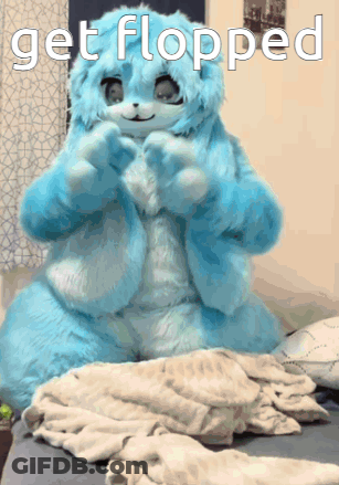 A Blue Stuffed Animal Is Sitting On A Bed With The Words Get Flopped Below It GIF