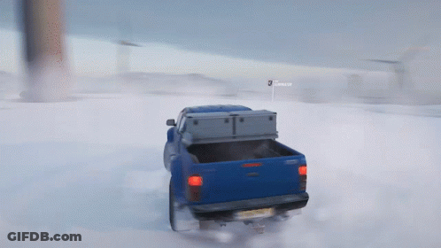 A Blue Truck Is Driving Through The Snow With A Sign That Says Snooper GIF