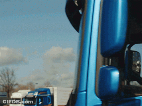 A Blue Truck Is Parked In Front Of A White Truck GIF