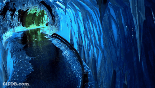A Blue Tunnel With Icicles And A Green Light GIF