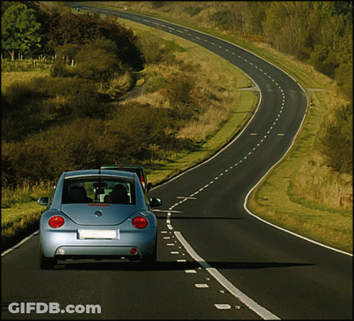 A Blue Volkswagen Beetle Is Driving Down A Road GIF