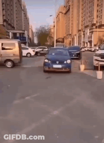 A Blue Volkswagen Car Is Parked On The Side Of A City Street . GIF