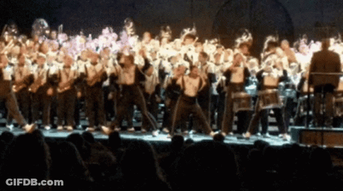 A Blurred Image Of A Marching Band Performing On A Stage GIF