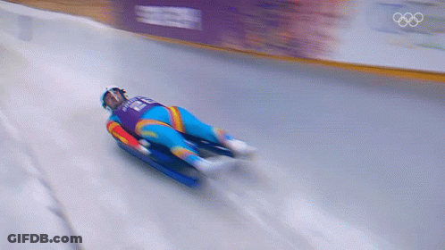 A Blurred Image Of A Person Sledding Down A Snowy Track With The Olympics Logo In The Background GIF