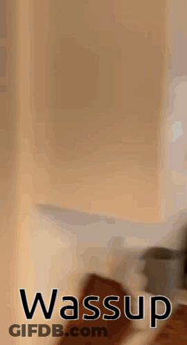 A Blurred Image Of A Person Standing Next To A Wall With The Word Wassup On It . GIF
