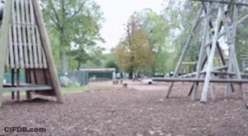 A Blurred Image Of A Playground In A Park With Trees In The Background GIF