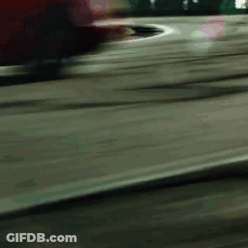 A Blurred Image Of A Red Car Driving Down A Road GIF