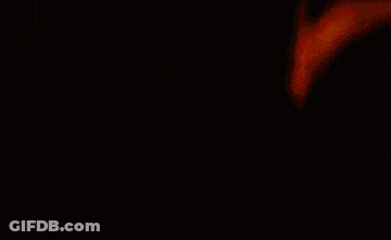 A Blurred Image Of A Red Yellow And Green Cube On A Black Background GIF
