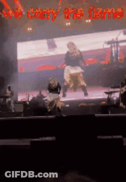 A Blurred Image Of A Stage With The Words We Carry The Flame GIF
