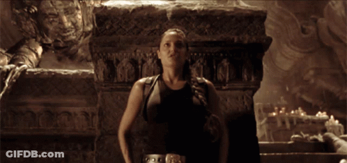 A Blurred Image Of A Woman Holding A Gun In Front Of A Stone Wall GIF