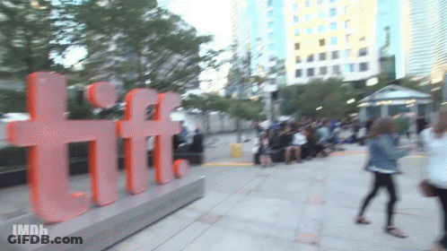 A Blurred Image Of People Walking In Front Of A Large Tiff Sign GIF