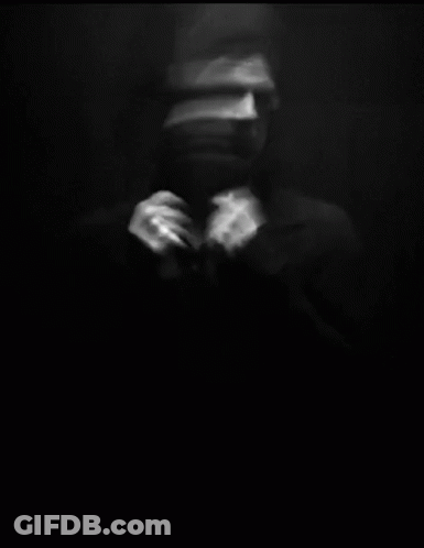 A Blurry Black And White Photo Of A Man Adjusting His Tie In A Dark Room . GIF