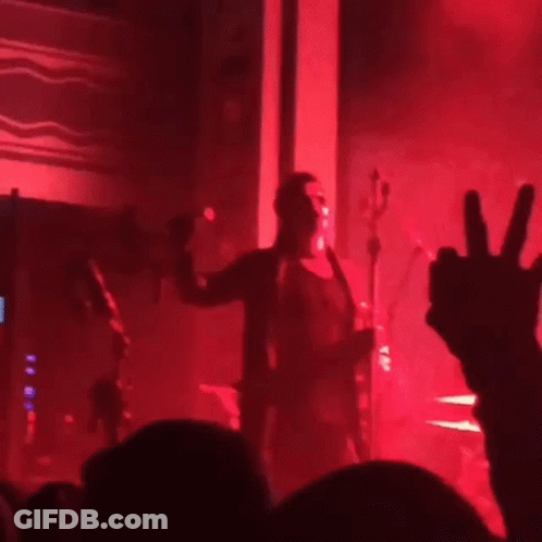 A Blurry Photo Of A Concert With Red Lights GIF